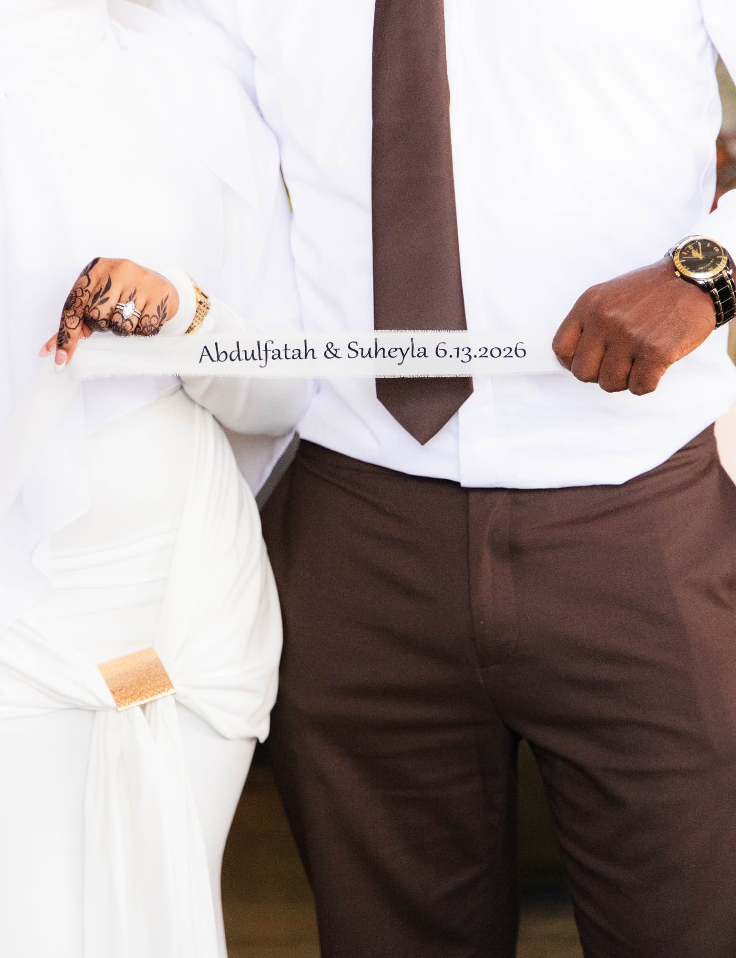 Couple holding a personalized ribbon reading Abdulfatah & Suheyla 6.13.2026