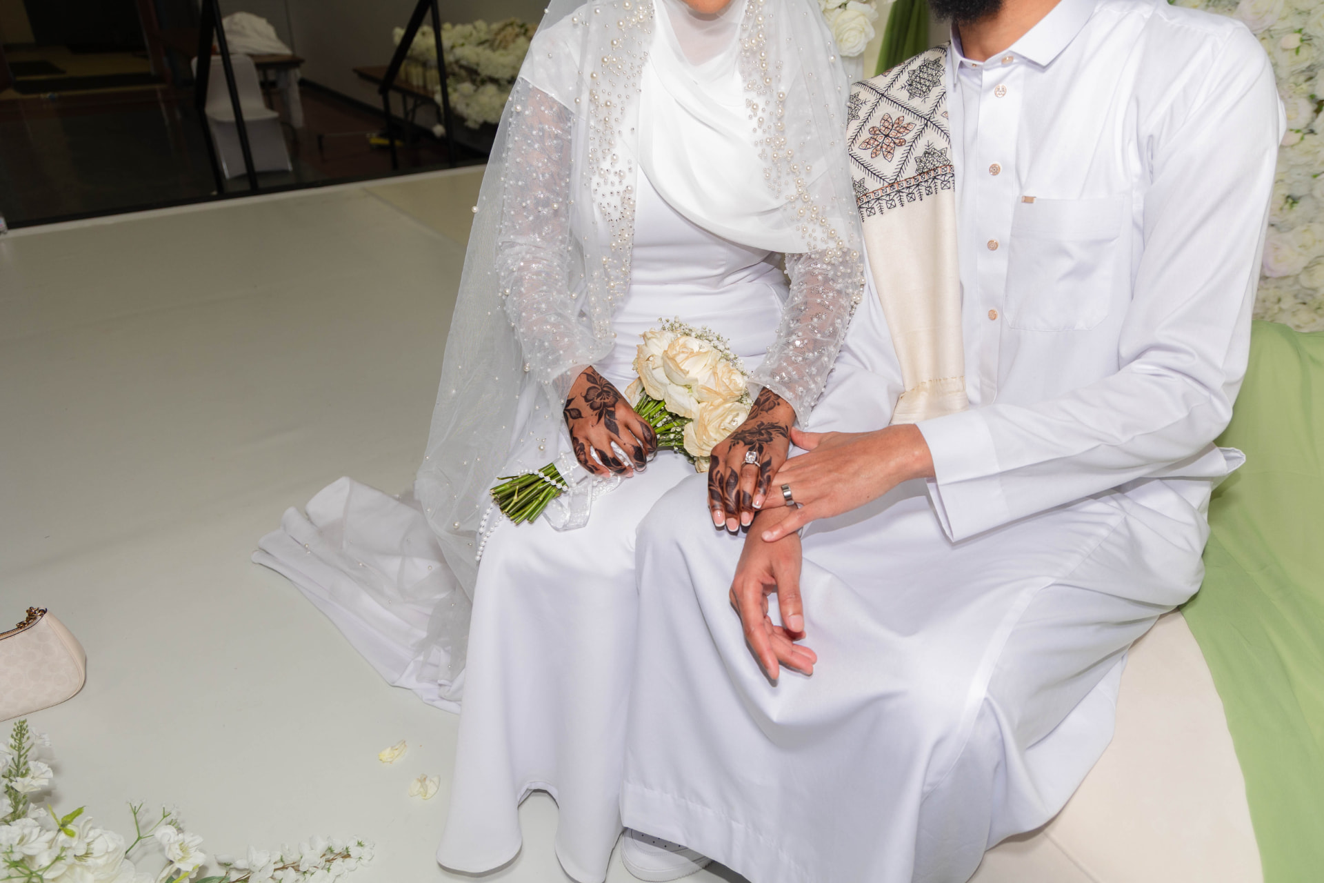 Close-up of a bride and groom's henna-detailed hands and rings