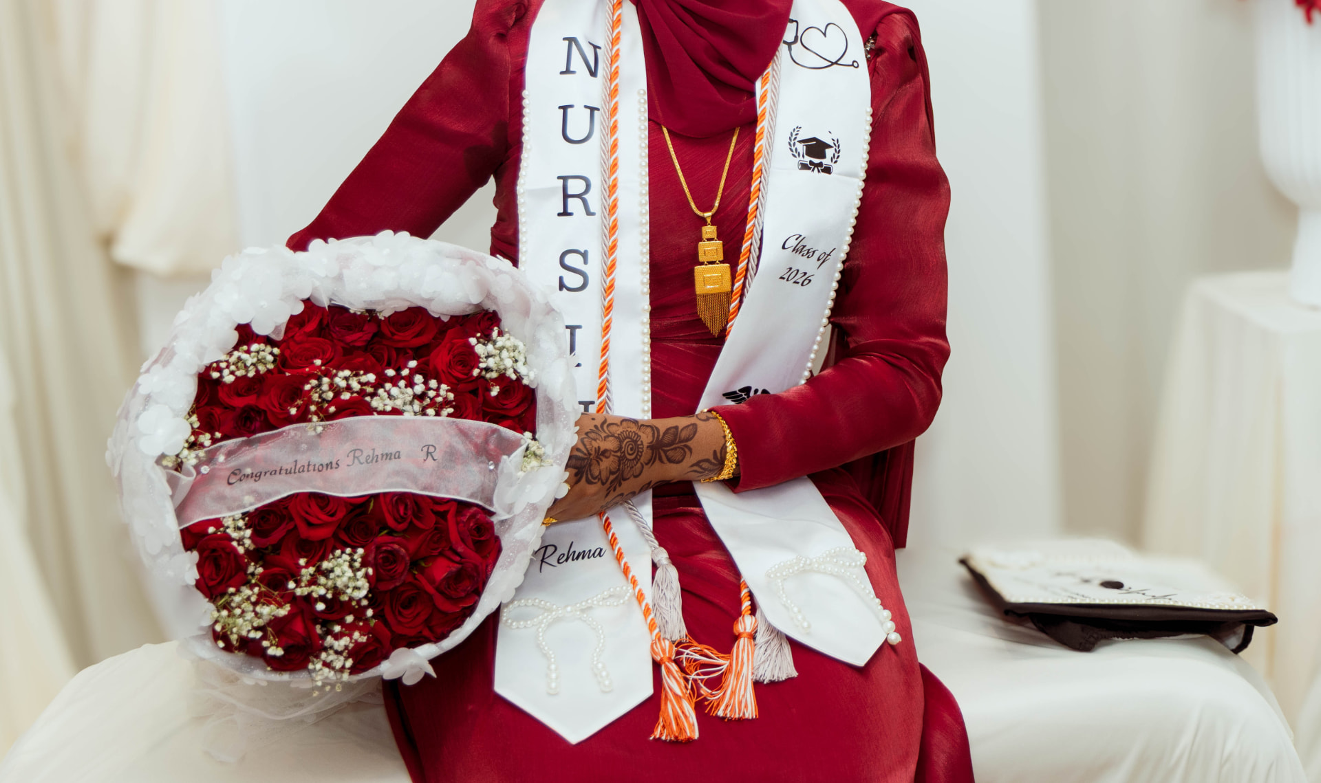 Close-up of a nursing graduate's stole, honor cords and red rose bouquet