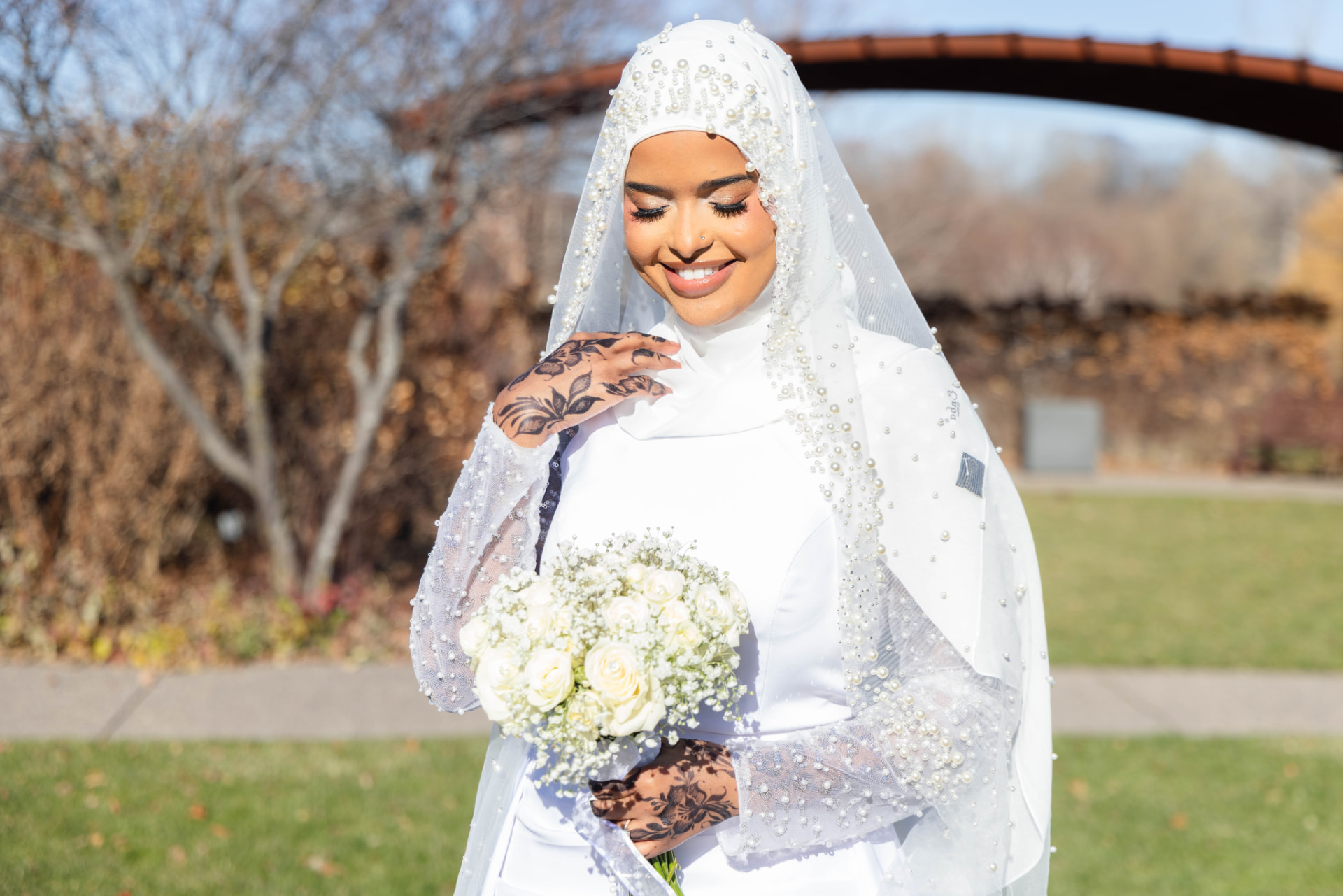 Bride in pearl-beaded veil holding a white rose bouquet